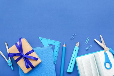 Mavi zemin üzerinde farklı kırtasiye malzemesi olan hediye kutusu
