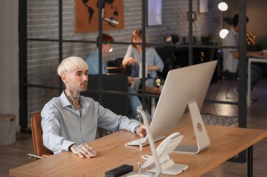 Erkek programcı geceleri ofiste bilgisayarla çalışıyor.