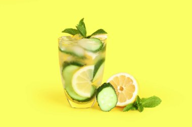 Bir bardak salatalıklı limonata ve sarı arka planda nane şekeri.