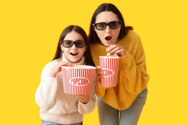 小女孩和她的母亲戴着带黄色背景爆米花的3D眼镜 — 图库照片