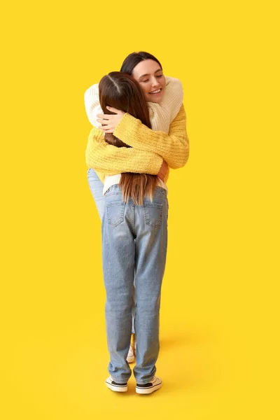Little Girl Her Mother Knitted Sweaters Hugging Yellow Background — Stock Photo, Image
