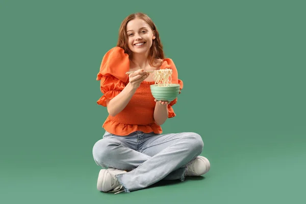 緑色の背景に座っている中華麺のボウルと若い女性 — ストック写真
