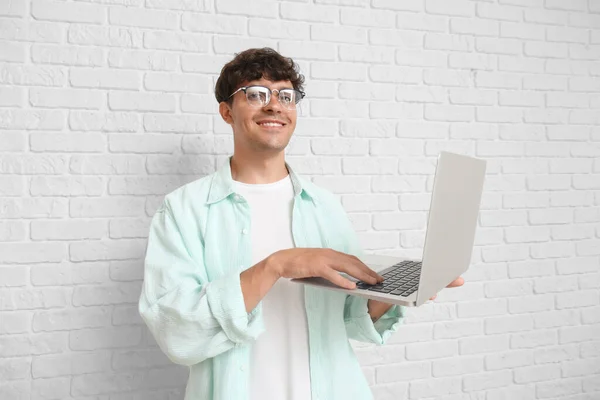 男性プログラマーは白いレンガの背景にラップトップで作業する — ストック写真