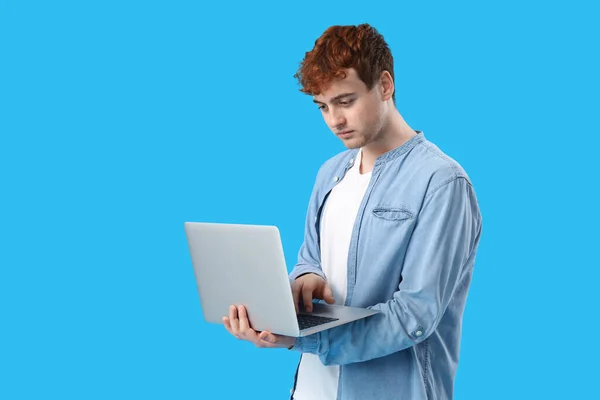青い背景のラップトップで作業する男性プログラマー — ストック写真