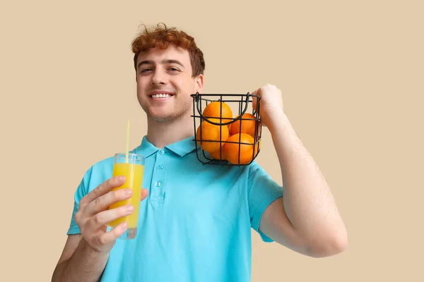Junger Mann Mit Orangen Und Einem Glas Saft Auf Beigem — Stockfoto