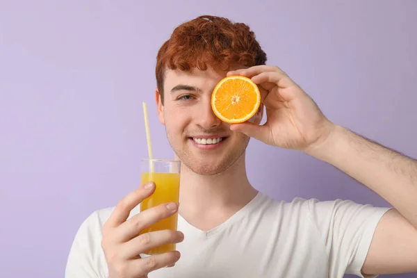 Junger Mann Mit Orange Und Einem Glas Saft Auf Fliederfarbenem — Stockfoto