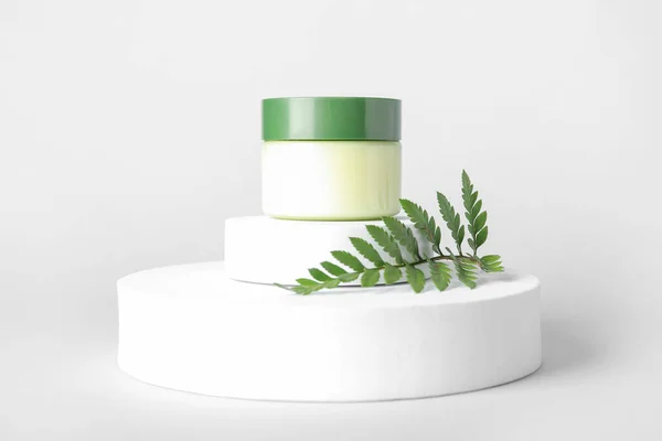 stock image Composition with jar of cosmetic product, plaster podiums and fern leaf on light background