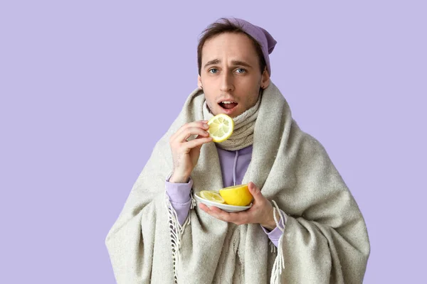 Leylak Arka Planında Limon Yiyen Hasta Genç Adam — Stok fotoğraf