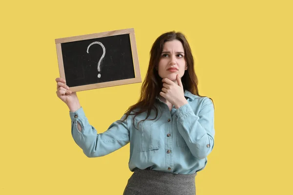 黄色の背景に疑問符で黒板を保持考えて女性教師 — ストック写真