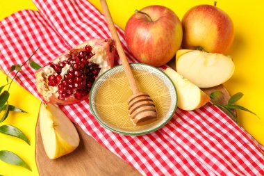 Sarı arka planda ballı ve olgun meyveli kompozisyon, yakın plan. Rosh hashanah (Yahudi Yeni Yılı) kutlaması