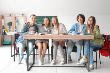 Sınıftaki masada çalışan bir grup genç öğrenci.