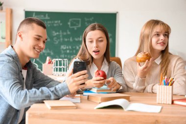 Sınıfta abur cubur yiyen bir grup genç öğrenci.