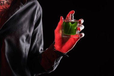 Siyah arka planda parfümlü dövmeli genç adam, yakın plan.