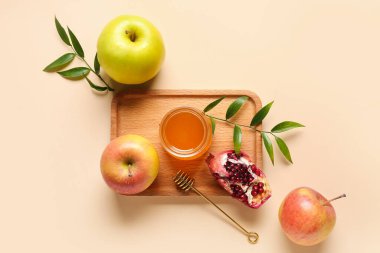 Bej arka planda, Rosh Hashanah kutlaması (Yahudi Yeni Yılı) için bal, nar ve elma dolu tahta tahta tahta tabela
