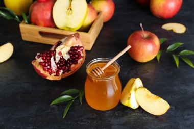 Rosh Hashanah kutlaması için kavanoz bal, nar ve elma (Yahudi Yeni Yılı) siyah masada