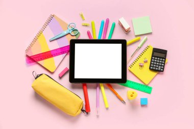 Pembe zemin üzerinde tablet ve hesap makinesi olan farklı bir kırtasiye.