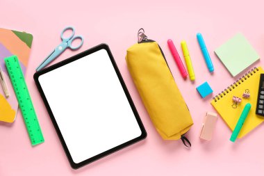 Pembe zemin üzerinde tablet ve hesap makinesi olan farklı bir kırtasiye.