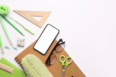 Gözlüklü cep telefonu ve beyaz arkaplanda farklı bir kırtasiye.