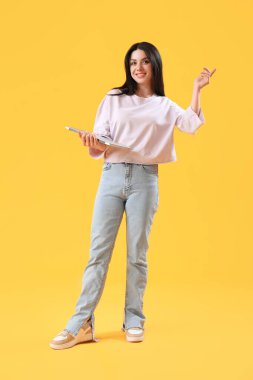 Female programmer with laptop on yellow background