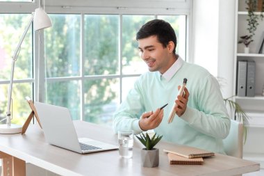 Not defteri olan genç bir adam evde iş görüşmesi yapıyor.