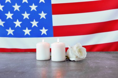 Mumlar ve gül çiçekleri Amerikan bayrağına karşı. Terörist Saldırıları Mağdurları İçin Ulusal Namaz ve Anma Günü