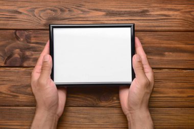 Ahşap arka planda boş fotoğraf çerçevesi tutan adam