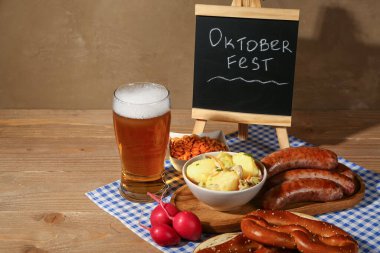 Bir bardak soğuk bira, kelime karatahta OKTOBERFEST ve ahşap arka planda farklı atıştırmalıklar