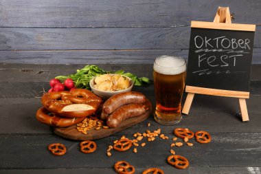 Bir bardak soğuk bira, üzerinde kelime yazan karatahta OKTOBERFEST ve farklı atıştırmalıklar.