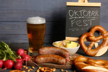 Bir bardak soğuk bira, üzerinde kelime yazan karatahta OKTOBERFEST ve farklı atıştırmalıklar.