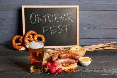 Bir bardak soğuk bira, üzerinde kelime yazan karatahta OKTOBERFEST ve farklı atıştırmalıklar.
