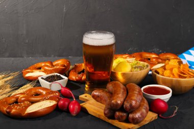 Bir bardak soğuk bira ve siyah arka planda farklı atıştırmalıklar. Ekim Festivali Kutlaması