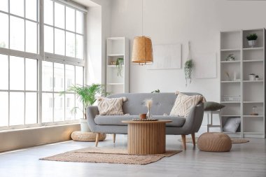 Gri kanepeli, ahşap sehpalı ve büyük pencereli aydınlık oturma odasının içi.