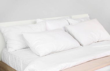 Yatak odasının içinde beyaz yastıklı büyük çift kişilik yatak.