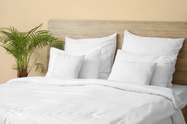 Yatak odasında beyaz yastıklar ve çiçekli rahat bir yatak.