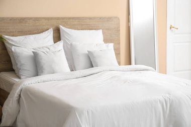 Yatak odasında beyaz yastıklar olan rahat bir yatak.