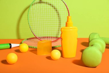 Renkli arka planda güneş kremi şişesi ve spor malzemesi kompozisyonu