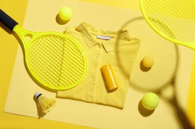 Renkli tişörtlü kompozisyon, güneş kremi şişesi ve spor malzemesi.
