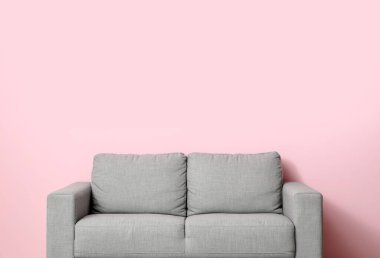 Pembe duvarın yanındaki rahat gri kanepe