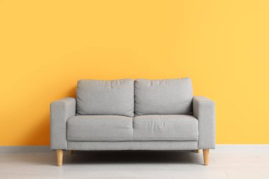 Turuncu duvarın yanındaki rahat gri kanepe