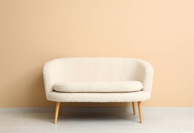 Bej duvarın yanındaki rahat beyaz kanepe.