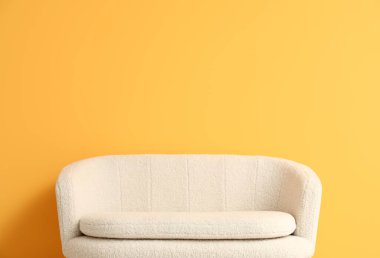 Turuncu duvarın yanındaki rahat beyaz kanepe.