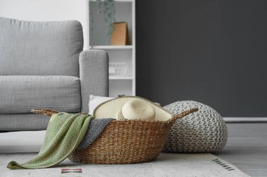 Oturma odasında şapka ve battaniyeli bir sepet.