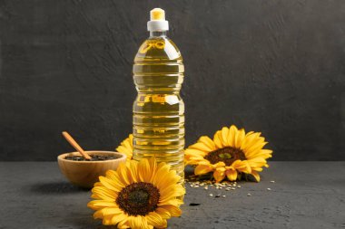 Siyah arka planda ayçiçekleri, tohumlar ve yağ şişesi