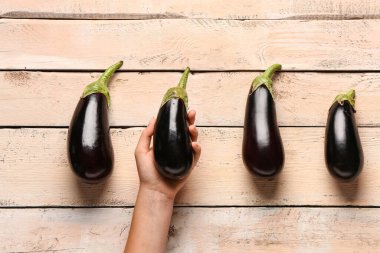 Hafif ahşap arka planda taze patlıcanlı bir kadın.