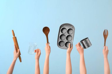 Mavi arka planda pişirme aletleri olan kadın elleri