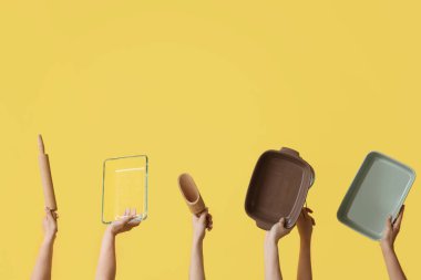 Sarı arka planda pişirme aletleri olan kadın eller.