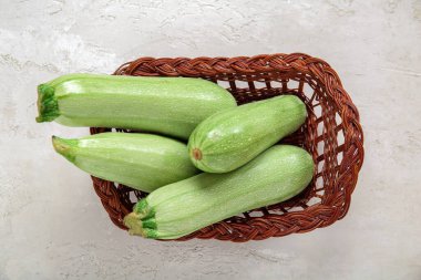 Açık arkaplanlı yeşil kabaklı hasır sepet.