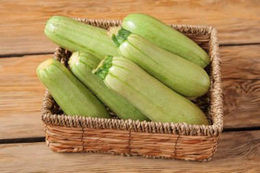 Ahşap zemin üzerinde taze yeşil kabak olan hasır kutu.