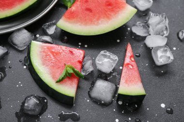 Siyah zemin üzerinde naneli ve buz küplü taze karpuz parçaları.
