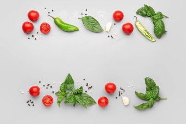 Taze fesleğen, kiraz domatesleri ve gri arka planda biber.